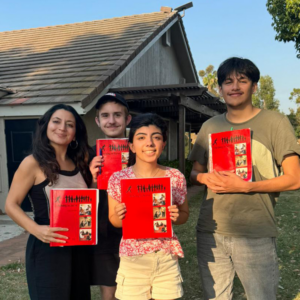 a mixed age group holding up red Ruhi books