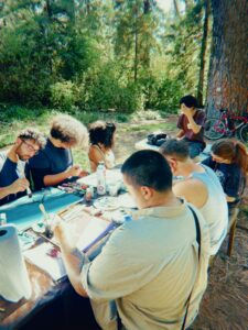 Group painting at a table surrounded by trees