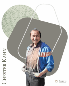 Chester Kahn, standing with hands in pockets with a taupe and green graphic behind him