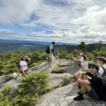 Some youth resting at the top of a hill after a hike